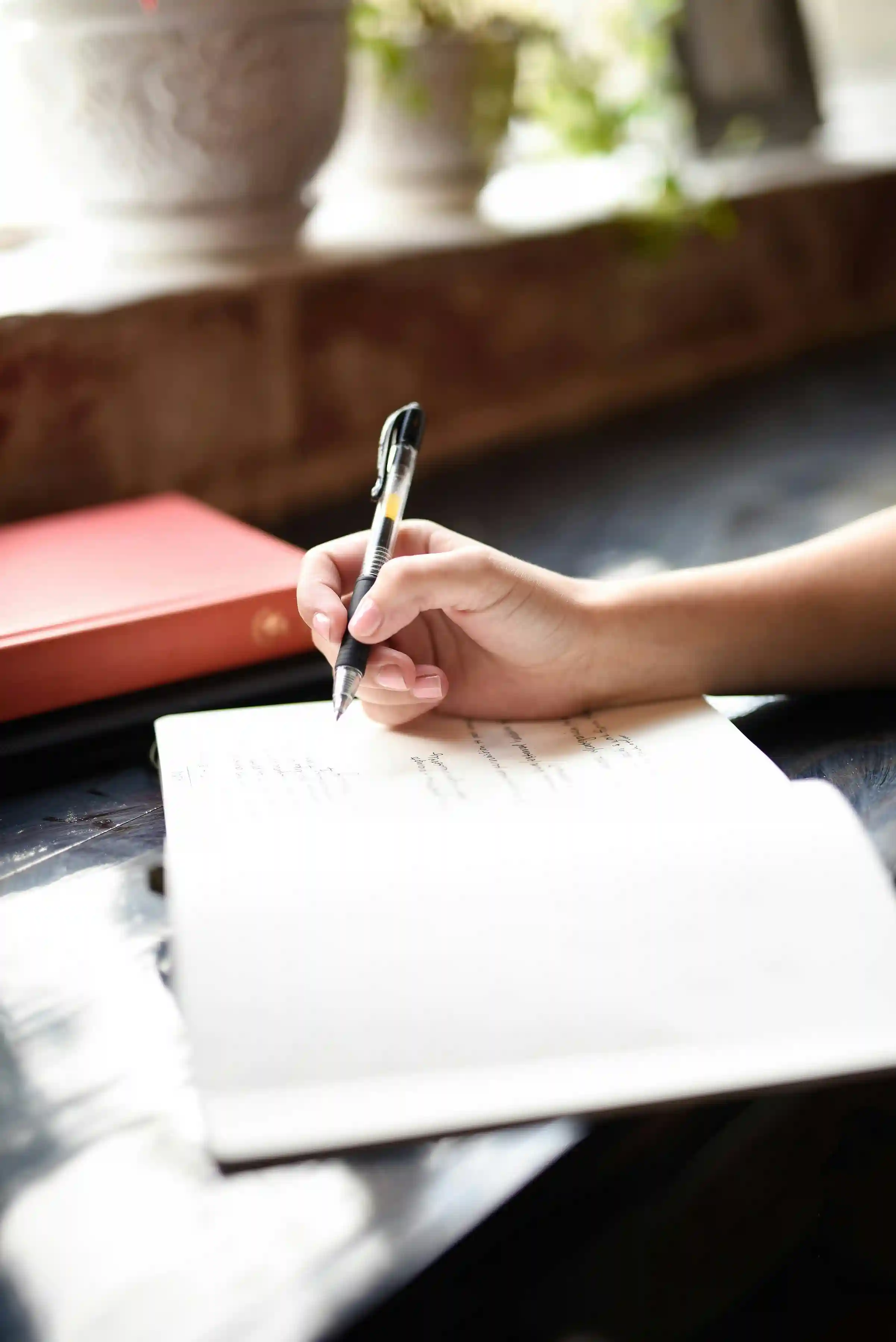 Une personne ecrivant sur une feuille de papier avec un stylo